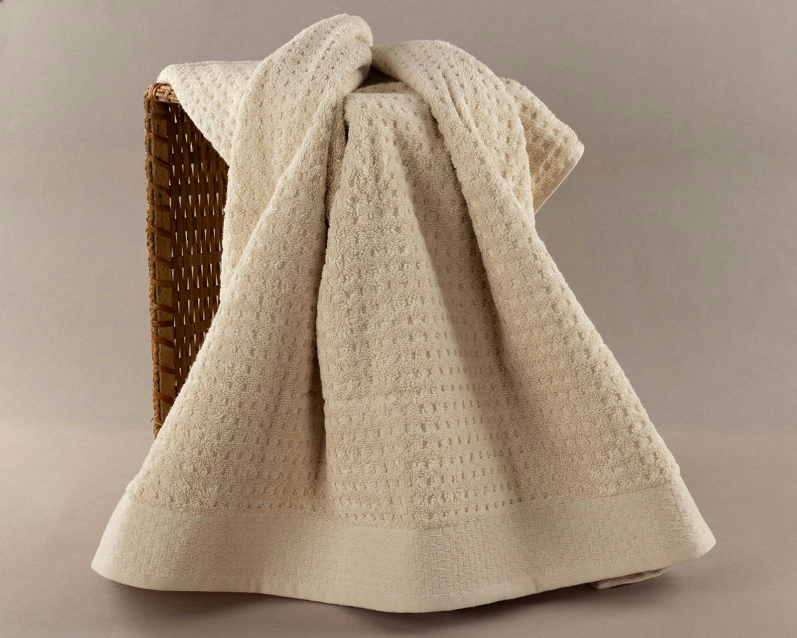A folded cream waffle-weave towel draped over a woven basket